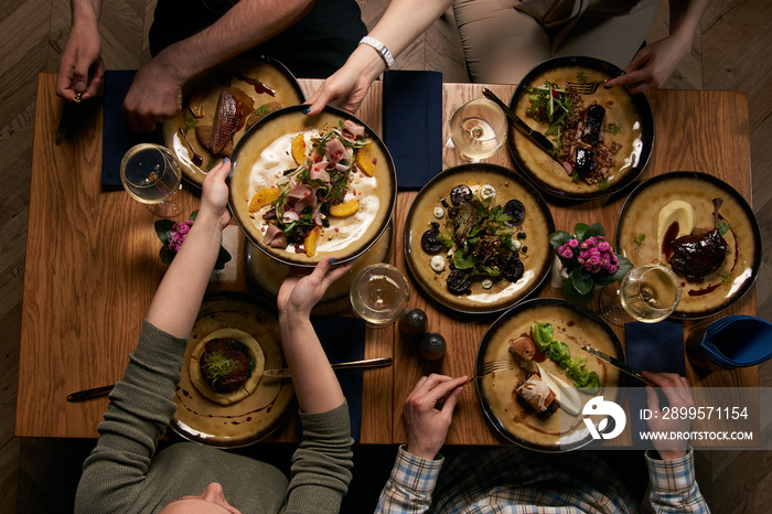 Company gathering for Christmas or New Year party dinner at festive table