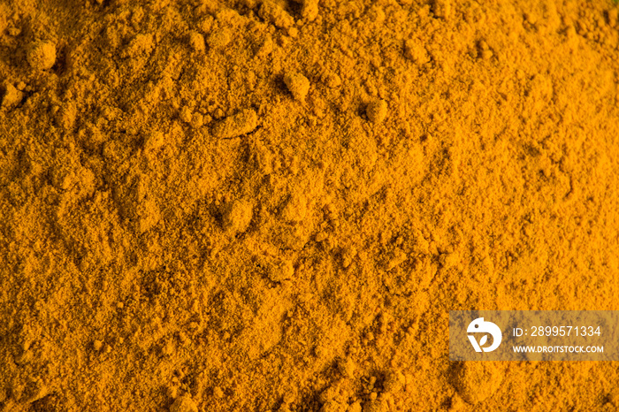 Orange abstract food background with copy space, natural dye, spice turmeric close up visa from top