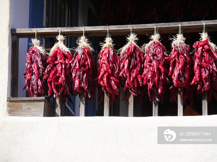 Bunches of dried red hot pepper hanging from the railing of a store