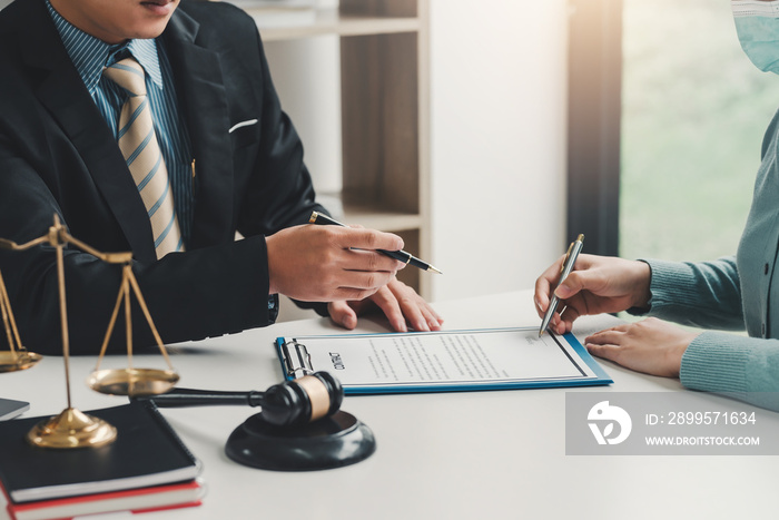 Close-up of a businessman hand pointing at a document to a client holding a pen to sign contract documents at the office.