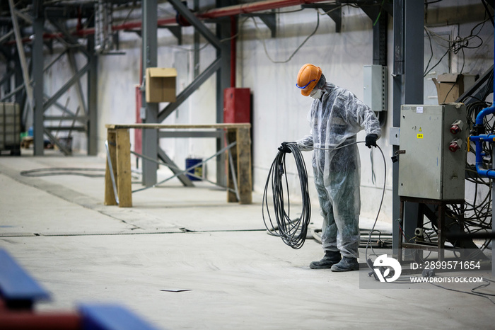 A builder in a work robe is engaged in the installation and construction of an industrial building at the Zvezda shipyard