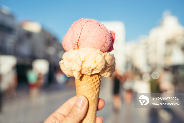 Woman’s hand holding ice cream in waffle cone.