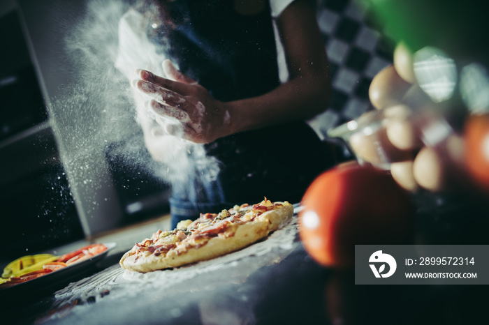 Hands in flour on black background. Making pizza in kitchen.