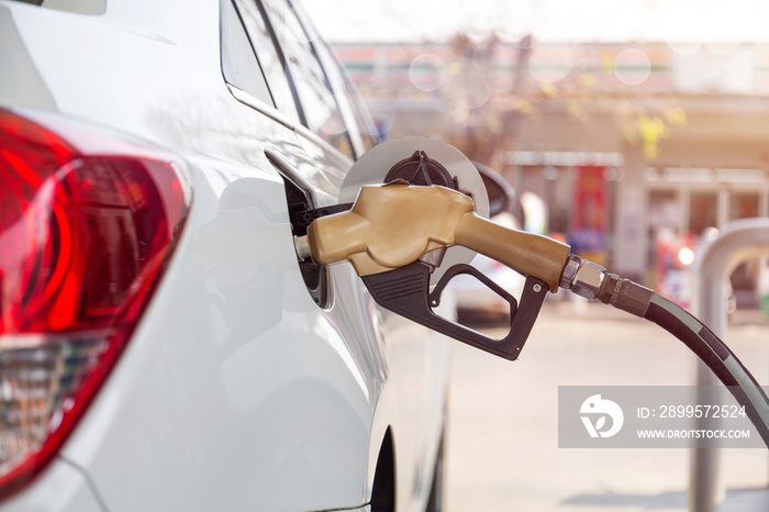 Closeup of woman pumping gasoline fuel in car at gas station. Petrol or gasoline being pumped into a motor vehicle car.