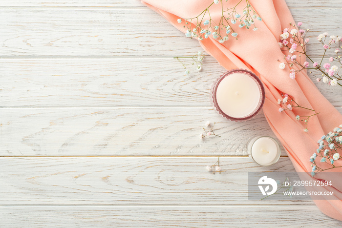 Hello spring concept. Top view photo of candles in glasses gypsophila flowers and pink scarf on grey wooden desk background with copyspace