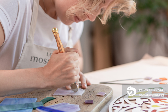 Artist cutting sheets of stained glass into small mosaic squares. Close-up