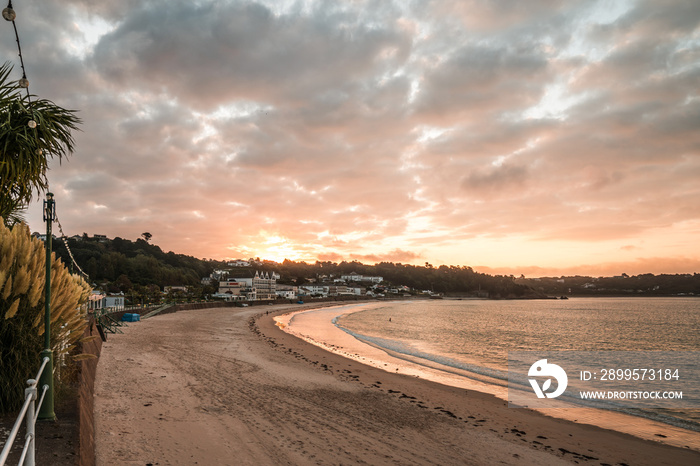 St Brelades Bay channel island of Jersey sunset sunrise dawn stunning vibrant orange sky beautiful seashore sand beach in morning and evening hotel clouds horizon reflecting sun on ocean uk holiday