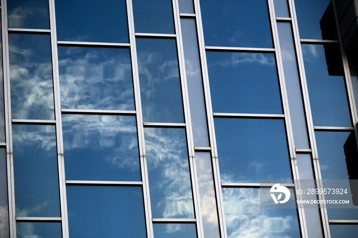 blue sky and clouds reflected from abstract glass windows in alternating shapes and tints