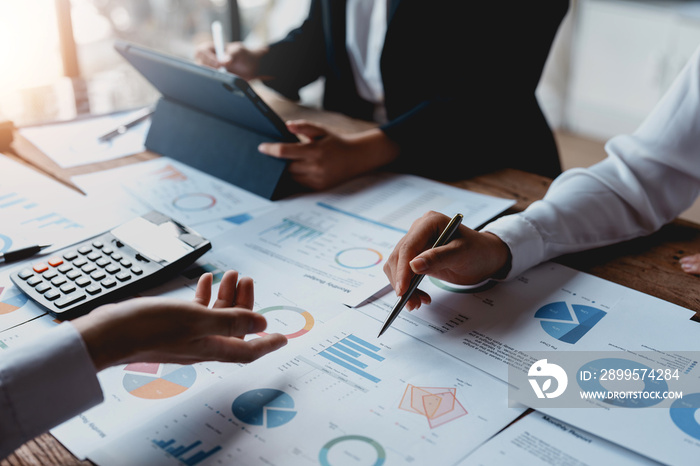 Image of a group of business people meeting using a tablet and calculating calculator to plan, analyze, graph and chart their organization’s growth to plan future business expansion.