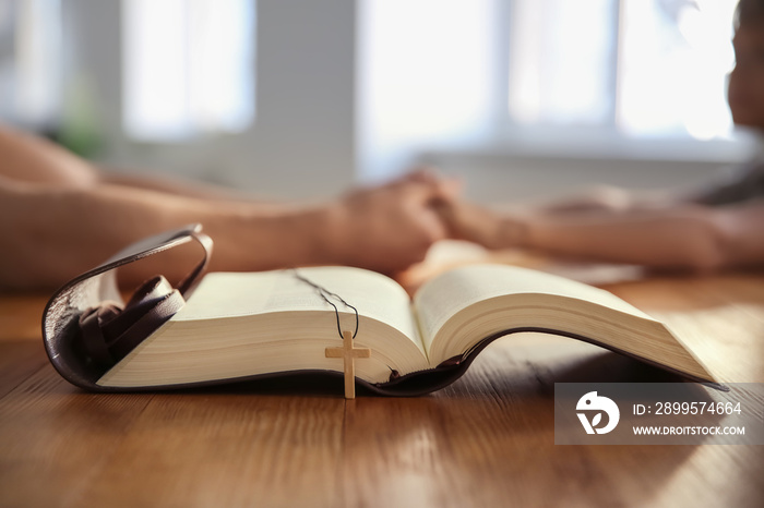 Open Bible with cross on wooden table