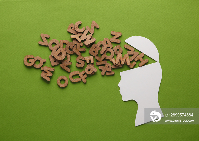 Paper-cut open human head with letters on a green background. The concept of mental health, open mind