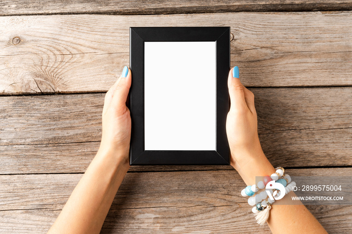 Young woman holding empty picture frame with copyspace. Mockup