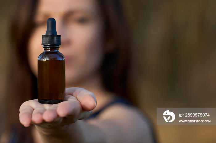 Woman holding a bottle of dietary supplements or essential oil in her hands. The concept of a healthy lifestyle.