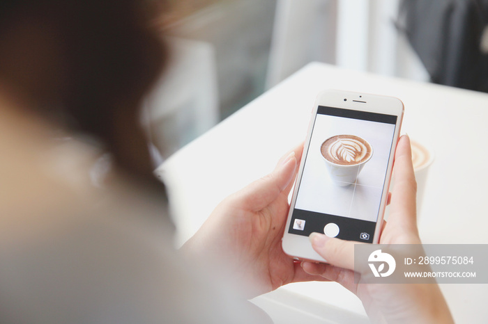 Young woman taking coffee picture with smartphone