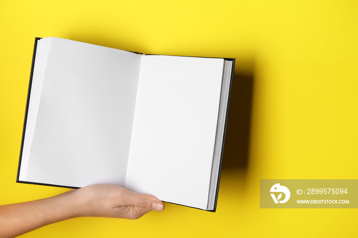 Woman holding open book on color background, closeup