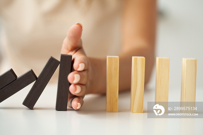 Hand of woman stopping and protect wooden block falling