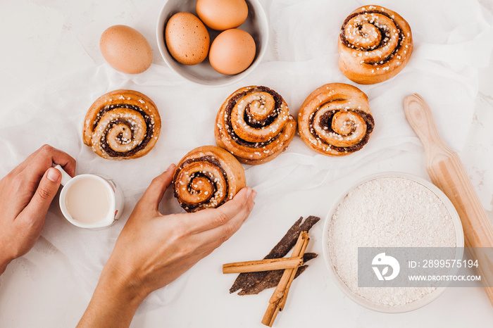 hands of woman making cinnamon rolls at table, recipe ingredients