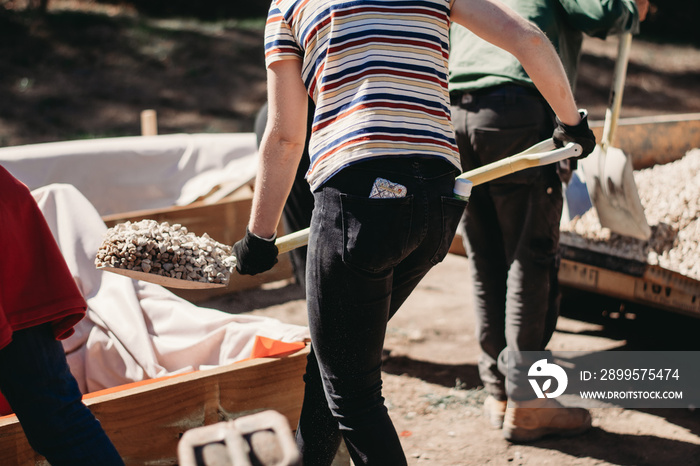 Woman shovelling gravel to build a wicking bed