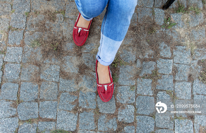 Womens foot close up in jeans and red loafers