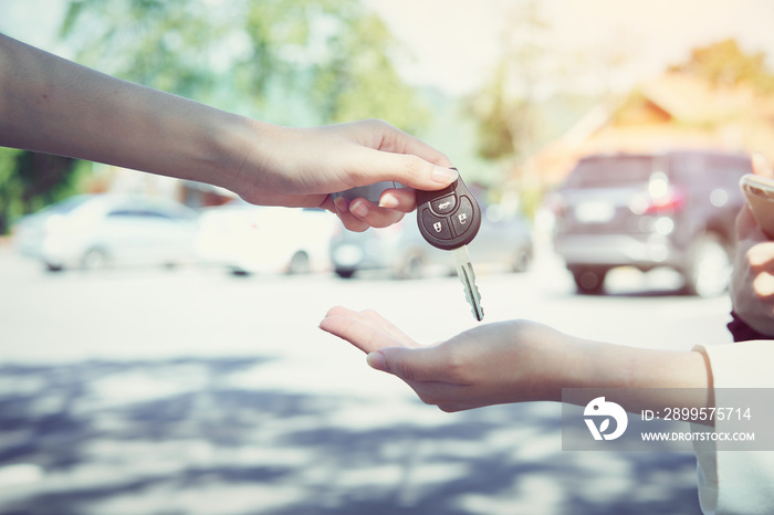 Woman’s hand give the car key and blurred background.