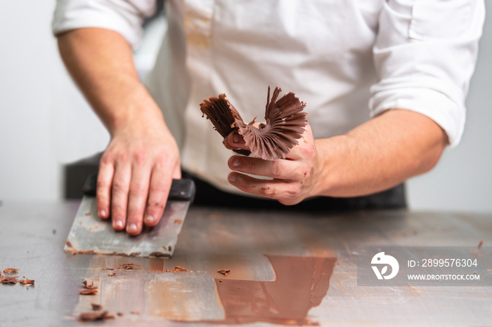 Professional confectioner making chocolate sweets at confectionery shop .