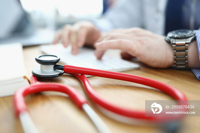 Doctor is typing on keyboard next to stethoscope