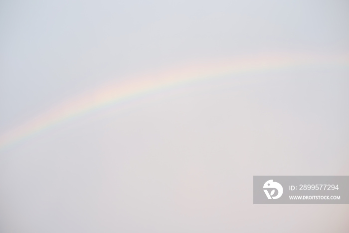 A rainbow on the background of the defocused sky as a background. Defocused bright sky after rain.