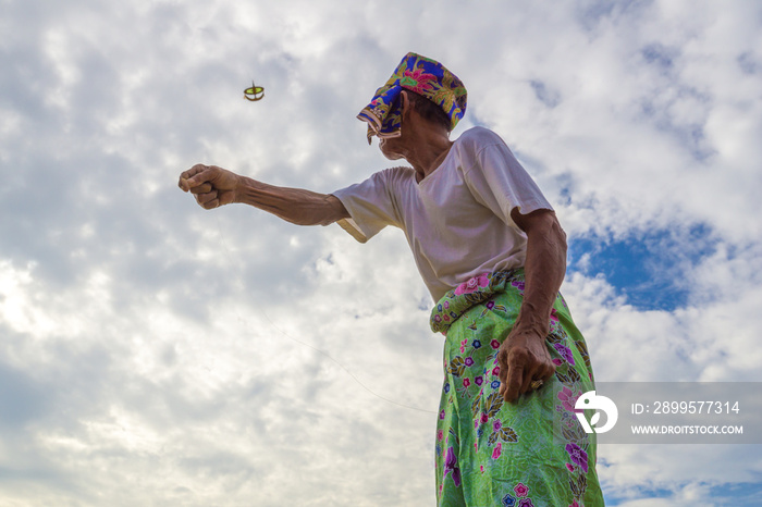 Unidentified man is playing the traditional moon kite or locally known as  Wau Bulan  in Kelantan, Malaysia.