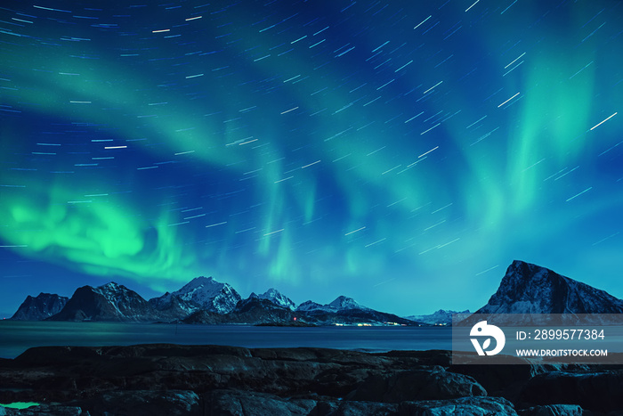 Northern Lights, Aurora Borealis shining green in night starry sky with star tracks at winter Lofoten Islands, Norway