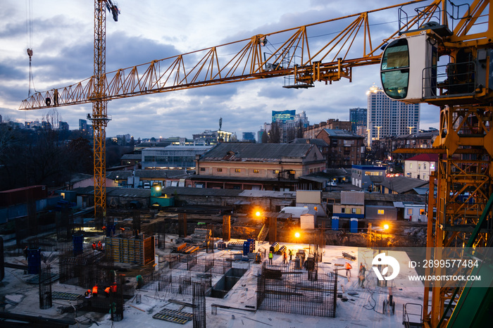 Construction site and cranes in the early evening. Workers on the crane and construction site