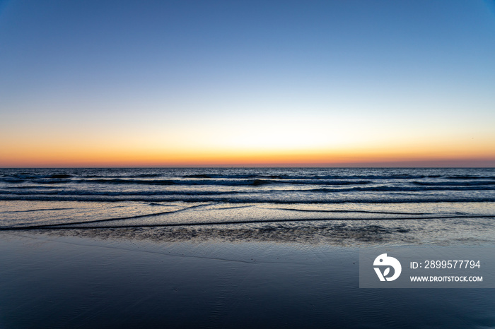 Sundown at the Dutch coastline between Noordwijk and Zandvoort. On the clear bright yellow and orange horizon.