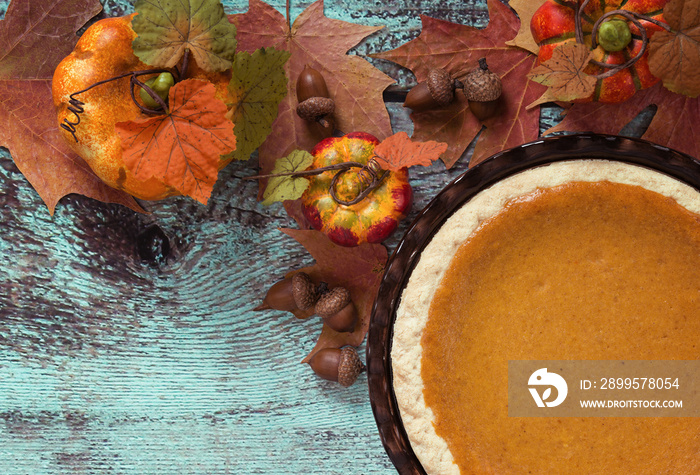 Pumpkin pie with autumn leaves and decorations against vintage wooden table. Top view.