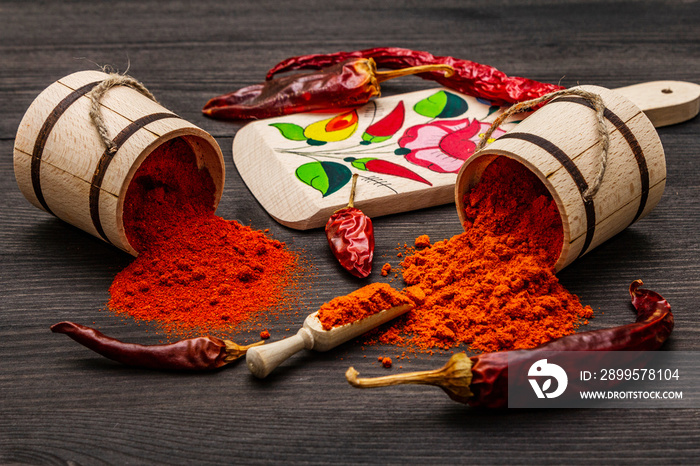 Magyar (Hungarian) red sweet and hot paprika powder. Traditional pattern on a cutting board, different varieties of dry pepper. Black wooden background