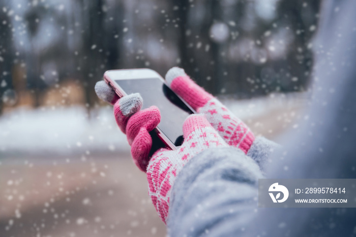 Woman using smartphone in winter with gloves for touch screens