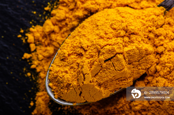 natural turmeric powder on a dark stone background