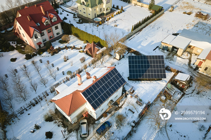 Aerial view of house roof with solar panels covered with snow melting down in winter end for producing clean energy. Concept of low effectivity of renewable electricity in northern region