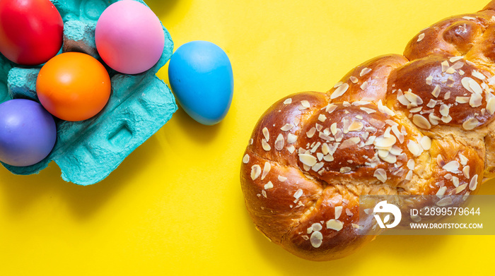 Easter eggs and tsoureki braid, greek easter sweet bread, on yellow color background