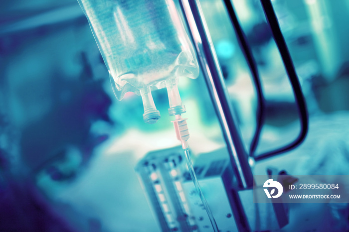 IV drip on the background of blurred hospital equipment and patient in the bed