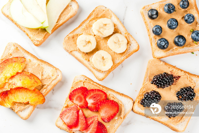 Traditional American and European summer breakfast: sandwiches of toast with peanut butter, berry, fruit apple, peach, blueberry, blueberry, strawberry, banana. White marble table. copy space top view