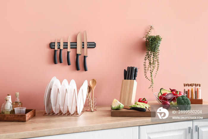 Counter with vegetables and utensils near color wall