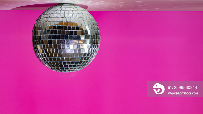 Mirror ball hanging from the ceiling in a modern pink room.