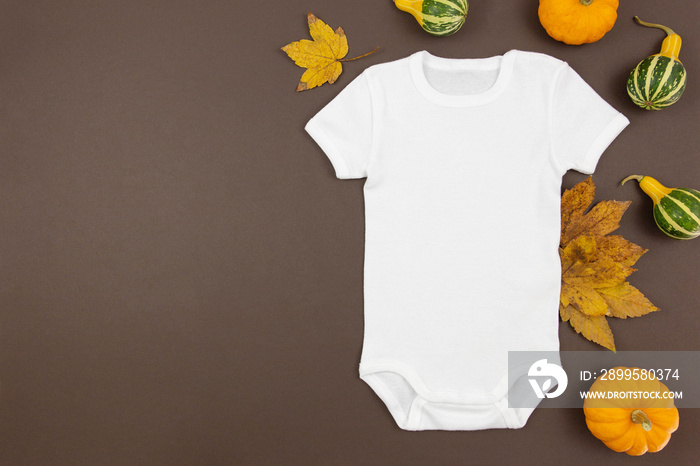 White baby girl or boy bodysuit flat lay mockup with pumpkins and fallen leaves on dark background. Design onesie template, print presentation mock up. Top view.