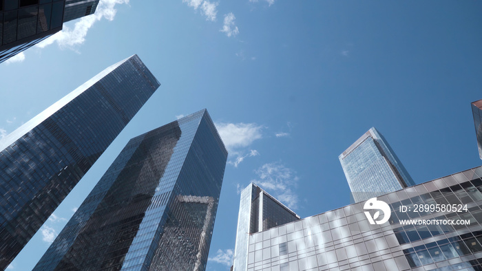 Bottom view of tops of glass skyscrapers on background blue sky. Action. Modern architecture of business centers reflecting blue sky. Dizzying view of modern glass skyscrapers