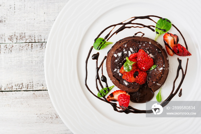 Chocolate fondant (cupcake) with strawberries and powdered sugar. Top view