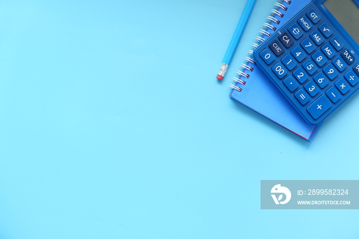 top view of blue calculator and notepad on color background