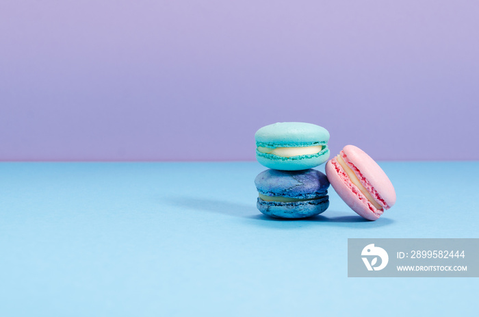 Three pink, green and blue macaroons on a blue and lavender copy space background.