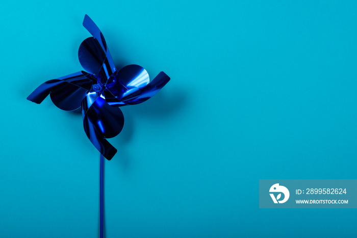 Blue pinwheel on blue background. Space for text on the right side of the image.