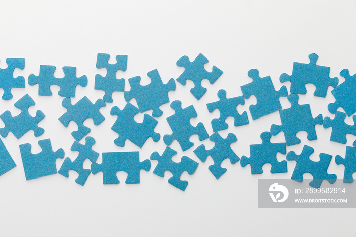 top view of scattered pieces of blue jigsaw puzzle on white background