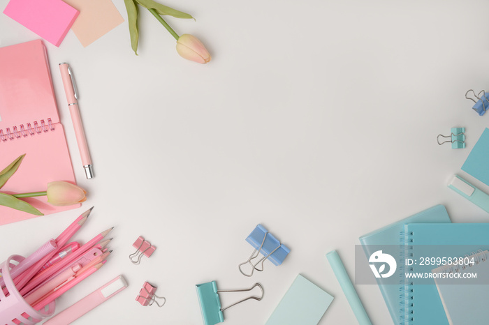 Top view notebook, stationery and pink tulips on white background.