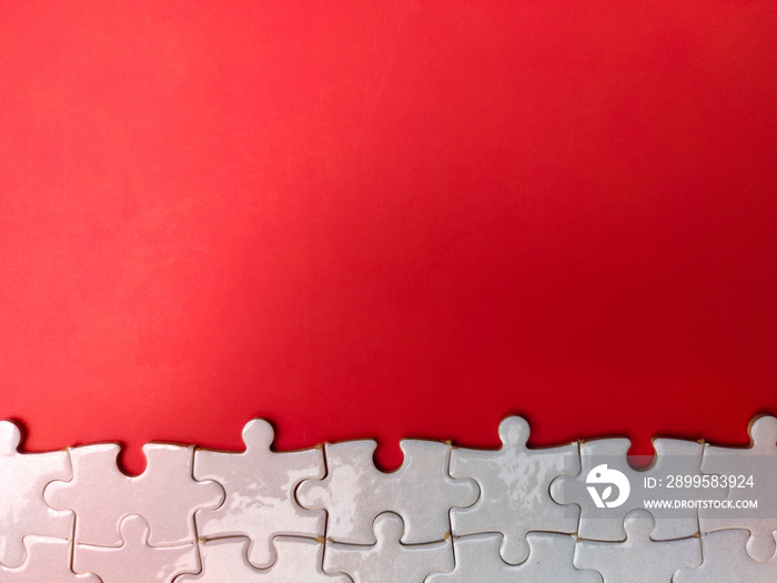 Unfinished white jigsaw puzzle pieces on red background